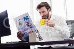 Businessman drinking coffee and reading newspapper