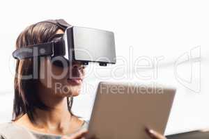 Businesswoman looking her tablet while using a virtual glasses