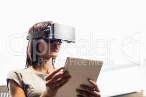 Businesswoman looking her tablet while using a virtual glasses