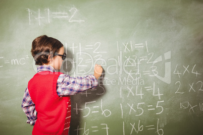 Boy writing with chalk on blackboard