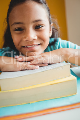 Girl leaning her head on pile of books