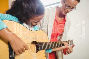 Girl learning how to play the guitar