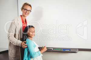 Teacher and pupil standing in front of whiteboard