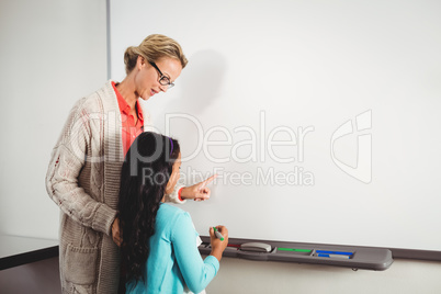 Teacher and pupil standing in front of whiteboard