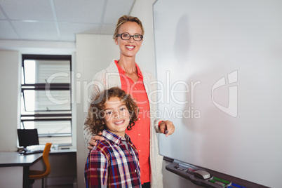 Teacher and pupil standing in front of whiteboard