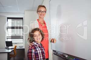 Teacher and pupil standing in front of whiteboard