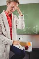 Sad teacher sitting on desk