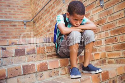 Sad schoolboy with his head on his knee