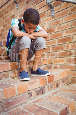 Sad schoolboy with his head on his knee