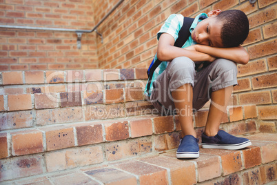 Sad schoolboy with his head on his knee