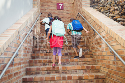 Three school kids climbing brick stairs