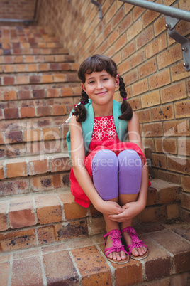 Smiling schoolgirl sitting in stairs