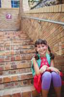 Smiling schoolgirl sitting in stairs