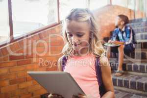Cute little schoolgirl looking at her digital tablet
