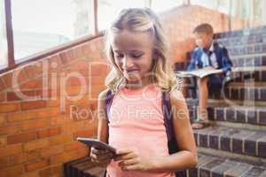 Cute little schoolgirl looking at her smartphone