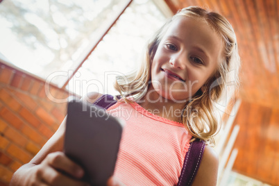 Cute little schoolgirl looking at her smartphone
