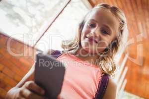 Cute little schoolgirl looking at her smartphone