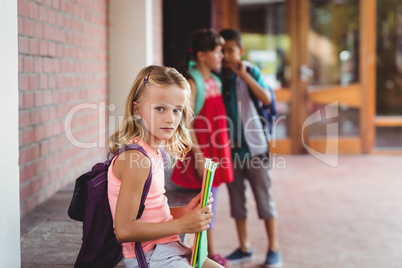 Seated blonde girl with a girl and boy in the background