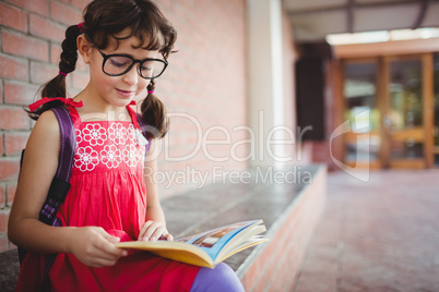 Seated schoolgirl reading a book