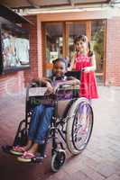 Girl pushing a friend in a wheelchair on a sunny day