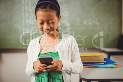 Schoolgirl smiling while holding a smartphone