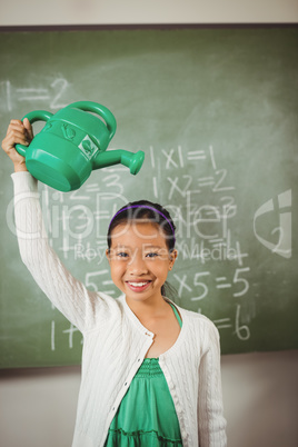 Smiling school girl using watering can on her