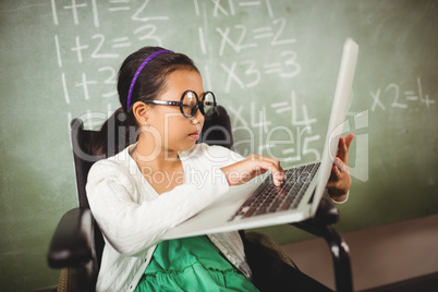 Little girl with big glasses typing on her laptop