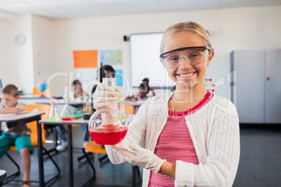 A pupil smiling at the camera with beaker