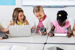 Pupil looking at rock with magnifying glass and classmates using