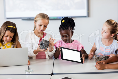 Pupils looking at rock while the others using technology