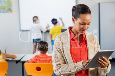 A teacher using tablet while pupils working