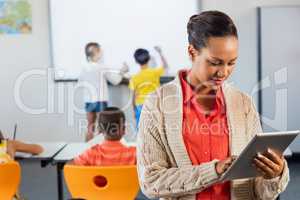 A teacher using tablet while pupils working