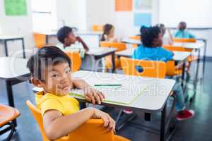 pupil sitting at his desk looking at camera in classroom