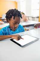 Little boy studying with tablet in classroom
