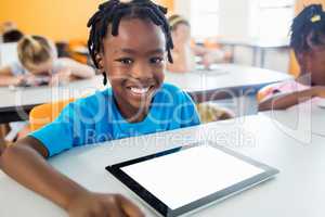 smiling pupil posing at desk with tablet pc