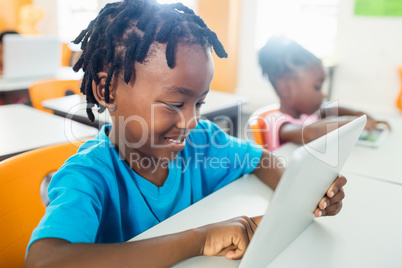 Side view of pupil using tablet pc in classroom