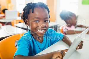 Happy pupil using tablet pc in classroom