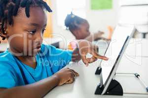 Side view of pupil using tablet pc in classroom