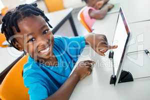 Happy pupil using tablet pc in classroom
