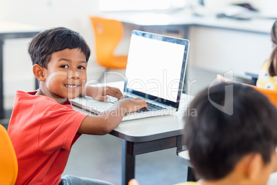 Cute pupil using laptop at desk