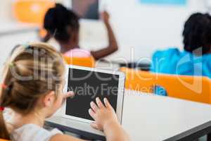 Rear view of pupil using tablet pc in classroom