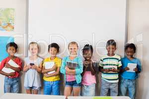 Smiling pupils standing with technology