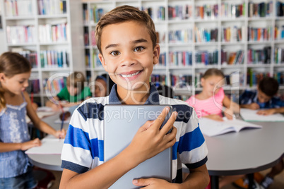 Boy looking at camera with tablet pc in library