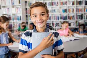 Boy looking at camera with tablet pc in library