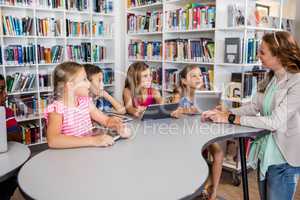 Young pretty teacher having lesson to children with their table
