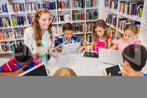 Young pretty teacher having lesson to children with their table