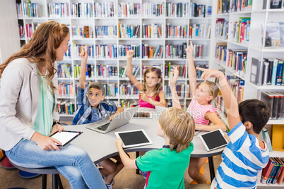 Young pretty teacher having lesson to children with their table