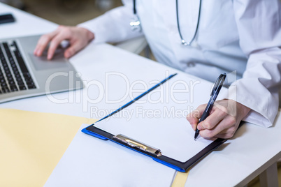 A woman vet taking notes and using her laptop