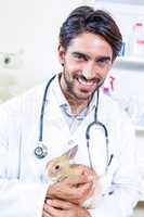 Portrait of smiling vet holding a rabbit