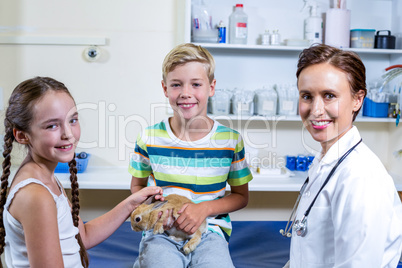 Little boy holding a rabbit surrounded by woman vet and little g